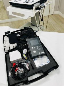 Kit oficial EPI® Advanced en la clínica FIX en Vigo, mostrando el dispositivo de electrólisis con pantalla, cables de conexión, porta-agujas, guantes, etc. Equipo completo para fisioterapia invasiva de alta precisión