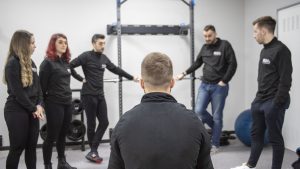 Imagen del equipo de profesionales colegiados conversando de forma distendida en una reunión de trabajo de nuestra clínica sanitaria en la sala de entrenamiento